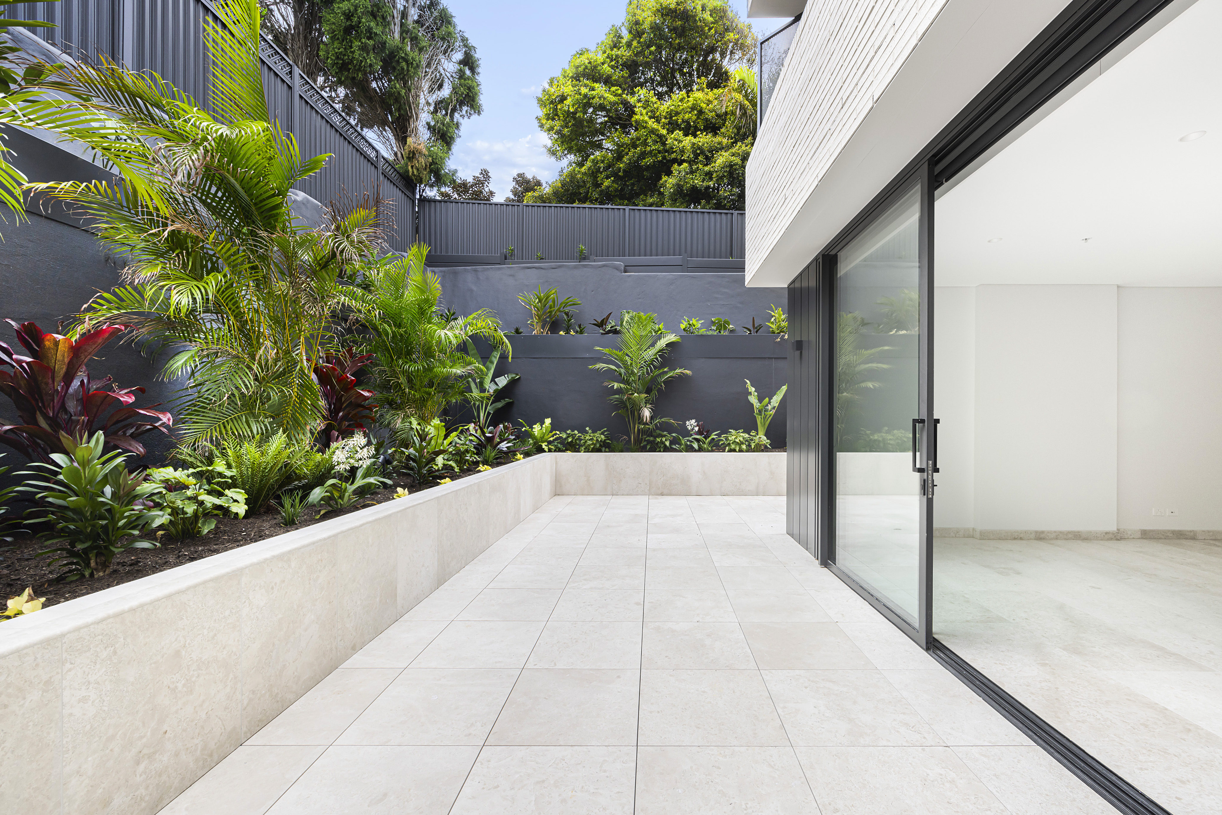 Outdoor terrace with large format tiles and garden privacy